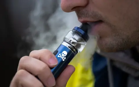 Persona vapeando un dispositivo con calavera, advirtiendo sobre los vapear efectos secundarios.