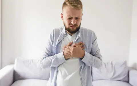 Mężczyzna z rękami na klatce piersiowej, cierpiący z powodu odbijania po jedzeniu.