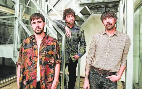 Los miembros de Lori Meyers posan juntos, con sus camisas estampadas y miradas serias, listos para su próxima actuación.