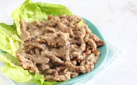 Straccetti di manzo succulenti serviti su foglie di lattuga fresca, un piatto invitante e saporito.