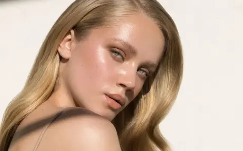 Delikatne rozjaśnianie brwi podkreśla naturalne piękno blondynki. Jej skóra lśni w słońcu.