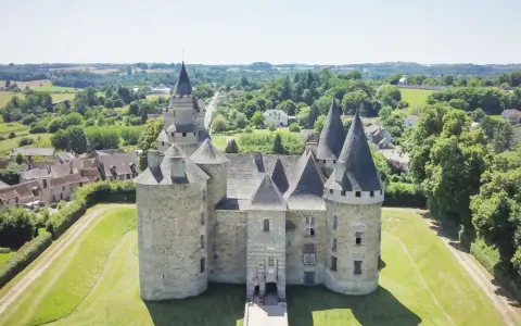 Le château de Bonneval, un joyau médiéval, se dresse fièrement au milieu d'un paysage verdoyant, entouré d'un village pittoresque.