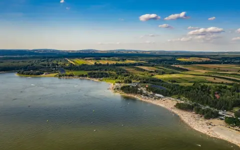 Letnie słońce nad **Jeziorem Chańcza**. Tłumy plażowiczów, zielone lasy i pola tworzą malowniczy krajobraz.