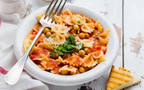 Farfalle-Pasta mit Kichererbsen in Tomatensauce, garniert mit Petersilie und Parmesan. Ein einfaches ceci rezept, perfekt für ein schnelles Mittagessen.