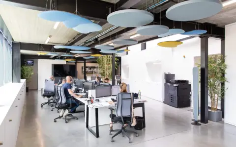 Bureau moderne avec des employés concentrés, des panneaux acoustiques colorés au plafond pour réduire le bruit au travail.
