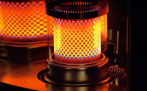 Estufa de parafina encendida, con llama naranja y azul visible a través de perforaciones. Pros y contras de su uso.