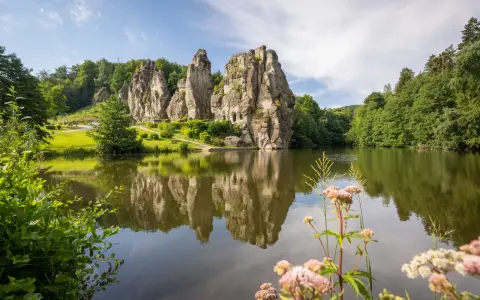 Ein idyllischer See spiegelt die imposanten Externsteine wider. Perfekt für eine entspannte Wanderung in dieser malerischen Landschaft.
