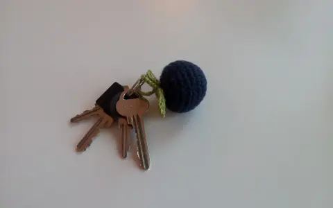En mörkblå virkad nyckelring i form av ett bär, fäst vid ett knippe nycklar.
