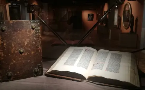 W muzeum diecezjalnym w Pelplinie eksponaty takie jak stary, oprawny księgozbiór i otwarta księga z tekstem przyciągają wzrok zwiedzających.