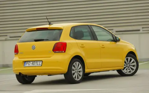 Żółty Volkswagen Polo widziany z tyłu, z widocznym tylnym światłem i tablicą rejestracyjną.