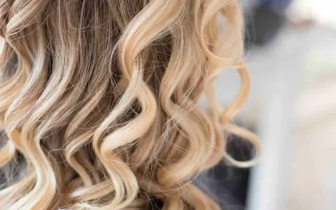 Falujące włosy z pasemkami blond z jasnym brązem, tworzące efekt słonecznych refleksów.