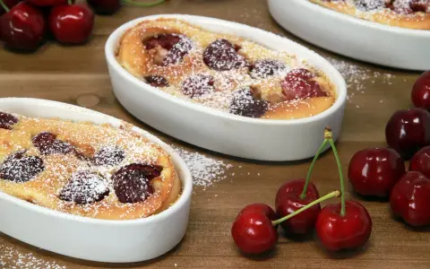 Deux clafoutis aux cerises, une spécialité auvergnate sucrée, saupoudrés de sucre glace, avec des cerises fraîches sur le côté.