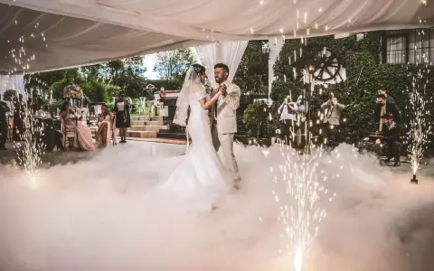 Brautpaar tanzt inmitten von Bodennebel und Funkenregen. Ein romantischer Moment, wie aus umgeschriebene Lieder zur Hochzeit.