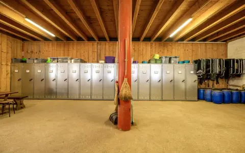 Reihe von Spinden, ideal zum Sattelschrank organisieren. Besen lehnen an rotem Pfosten.