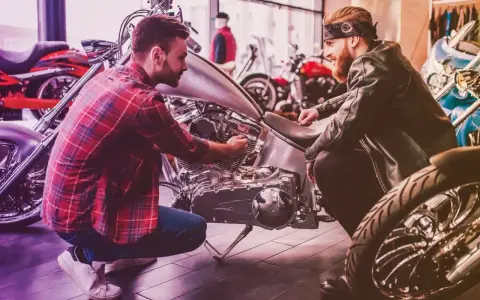 Due uomini esaminano un motore di moto custom. Uno mostra all'altro i dettagli, forse discutendo il costo della messa in strada della moto.