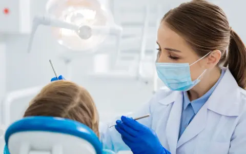 Dentystka bada uśmiech dziecka, by wykluczyć zapalenie dziąseł.