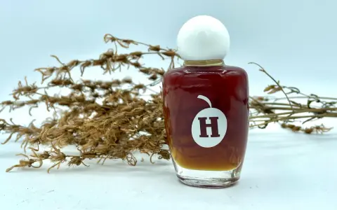 Frasco de aceite de hiperico con tapa blanca, junto a ramas secas.