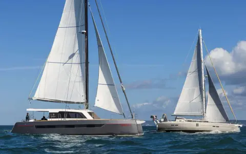 Deux grands voiliers naviguent sur une mer bleue sous un ciel clair.