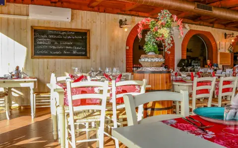 Interno di un ristorante di carne a Rimini centro, con tavoli apparecchiati e un menu scritto a mano.