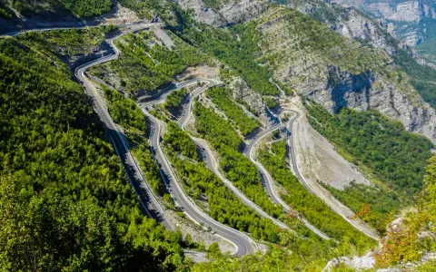 W serpentynach albania trasa pnie się po stromych zboczach gór, otoczona bujną zielenią.