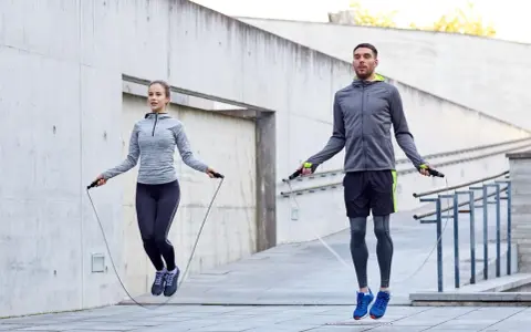 Ein Paar macht ein intensives **Springseil Workout** im Freien vor einer Betonwand.