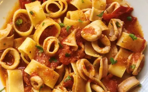 Pasta con calamares, un plato italiano lleno de sabor. Los calamares se mezclan con trozos de tomate y perejil fresco, creando una deliciosa combinación.