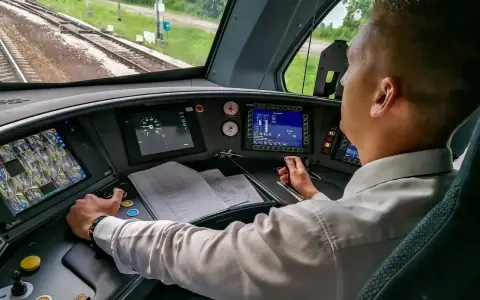 Maszynista w kabinie steruje pociągiem. Zastanawiasz się, ile zarabia maszynista? To odpowiedzialna praca.
