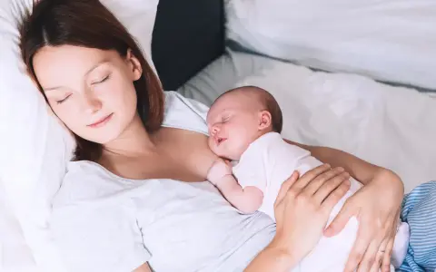 Matka śpi z dzieckiem przy piersi, doświadczając piękna laktacji.
