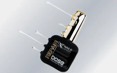 Czarna buteleczka z produktem do paznokci "base" od Nails Company, z płynnym, przezroczystym produktem wypływającym z butelki.