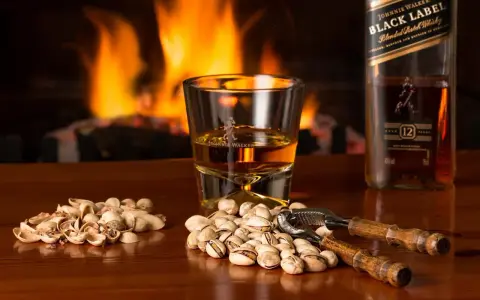 Przy kominku, kieliszek Johnnie Walker i pistacje. Idealny wieczór, czy whisky się chłodzi?