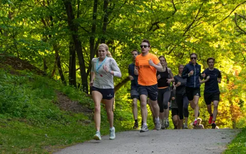 En grupp löpare tränar för en marathon distans i en grönskande park.