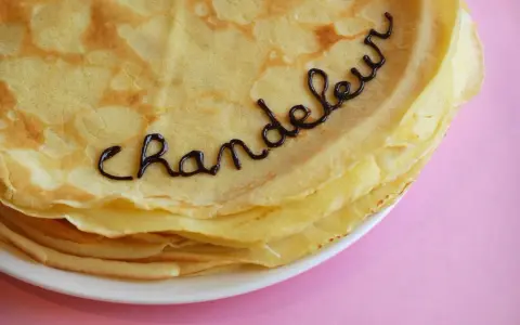 Une pile de crêpes dorées, décorées avec du chocolat formant le mot "Chandeleur". Un délice pour célébrer qu'est-ce que la Chandeleur.