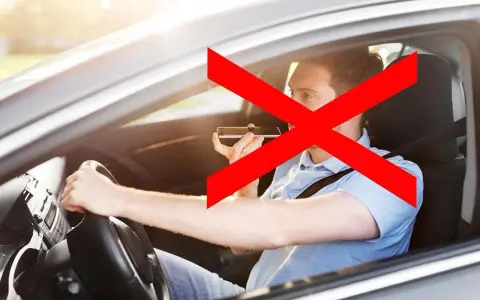 Uomo al volante che usa il cellulare, vietato dall'art. 173 CDS. La croce rossa indica il divieto.