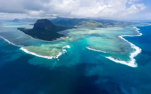 Majestatyczny Le Morne Brabant góruje nad turkusową laguną Mauritiusa. Woda mieni się odcieniami błękitu i zieleni, a białe fale rozbijają się o rafę.