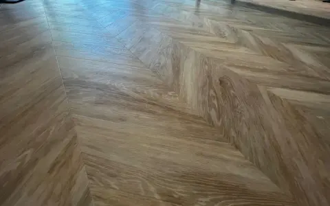 Drewniane panele ułożone we wzór jodełki. Jaki podkład zastosowano pod panele?
