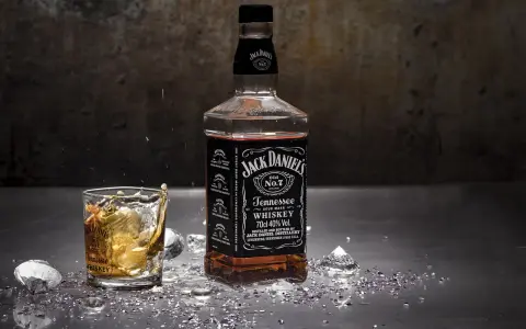 Butelka Jack Daniel's i szklanka z whisky, w której widać plusk. To klasyczny, old fashioned przepis na drinka.
