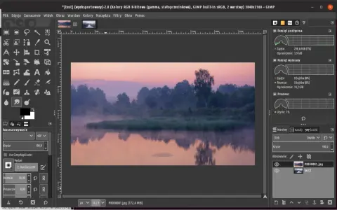 Mglisty poranek nad rzeką, edytowany w **GIMP 2.10**. Widać odbicie drzew w wodzie i wschód słońca.