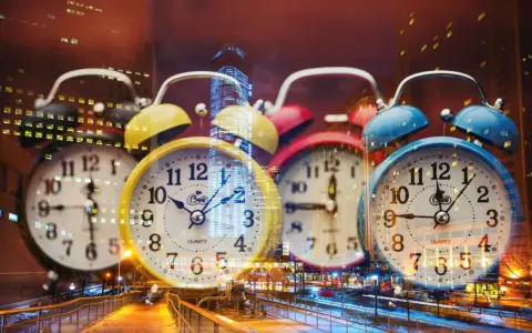 Wiele kolorowych budzików na tle nocnego miasta. 0404 znaczenie czasu, który nieustannie płynie.