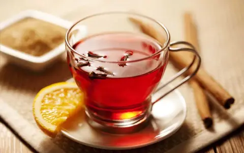 Té rojo con clavo y naranja, ideal para disfrutar de sus propiedades. Azúcar y canela al lado.