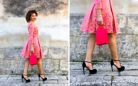 Elegancka stylizacja: jakie buty do różowej sukienki? Czarna, wysoka szpilka idealnie komponuje się z wzorzystą kreacją i torebką.