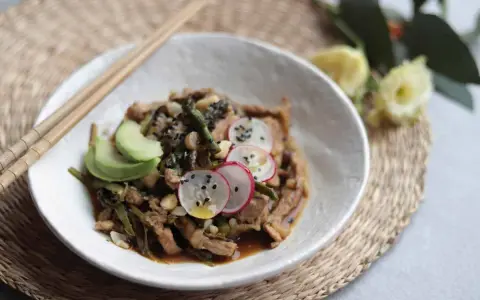Delicioso wok de verduras con tiras de carne, aguacate, rábano y semillas de sésamo.