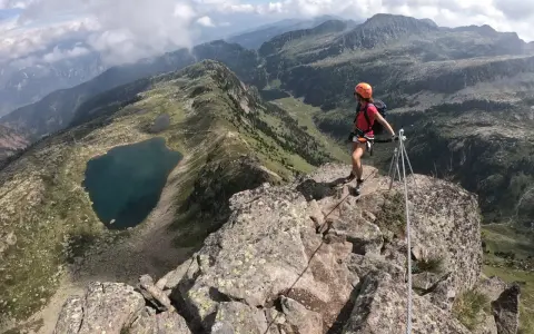 Escursionista in cima a una cresta rocciosa con vista sui laghi di Bombasel e sulle montagne circostanti.
