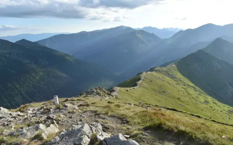 Widok na pasmo górskie Tatr z zielonymi zboczami i kamienistym szlakiem.