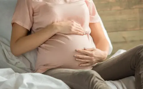 Kobieta w ciąży z dłońmi na brzuchu, martwiąca się o niskie erytrocyty w ciąży.