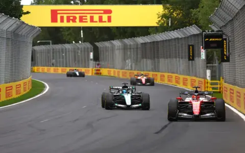 Coches de Fórmula 1 compiten en una curva, con el cartel de Pirelli al fondo. ¡Emocionantes noticias de Fórmula 1!