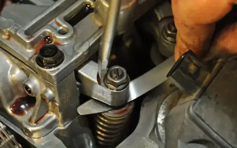Precyzyjna regulacja zaworów w silniku. Mechanik używa narzędzi do ustawienia luzów.