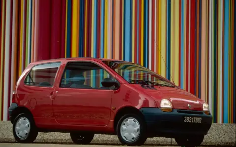 Renault Twingo 1 rouge devant un mur de bandes colorées verticales.