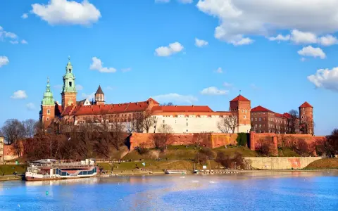 Zamek Królewski na Wawelu, z zielonymi wieżami i czerwonymi dachami, góruje nad Wisłą. Ciekawostki o jego historii czekają na odkrycie.