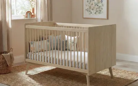 Cuna de madera clara con barrotes, colchón y cojines decorativos. Las medidas cuna son ideales para un cuarto infantil acogedor.