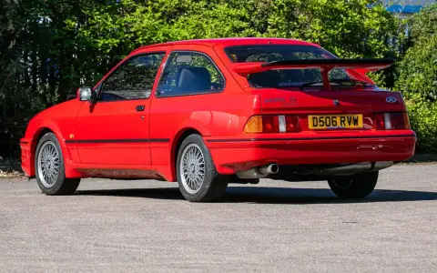 Roter Ford Sierra RS Cosworth mit großem Heckspoiler und markanten Felgen, bereit für die nächste Ausfahrt.